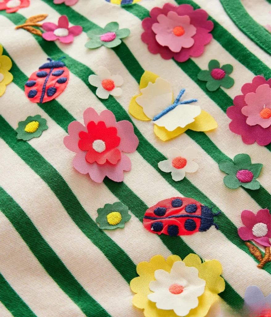 Raised fabric flowers, ladybirds and butterflies stitched on a green and cream striped top