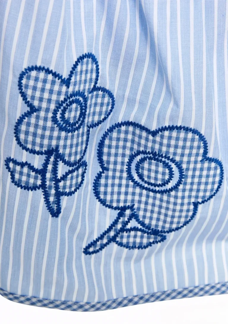 Blue gingham flower appliqués with zigzag stitch edges on a striped shirt