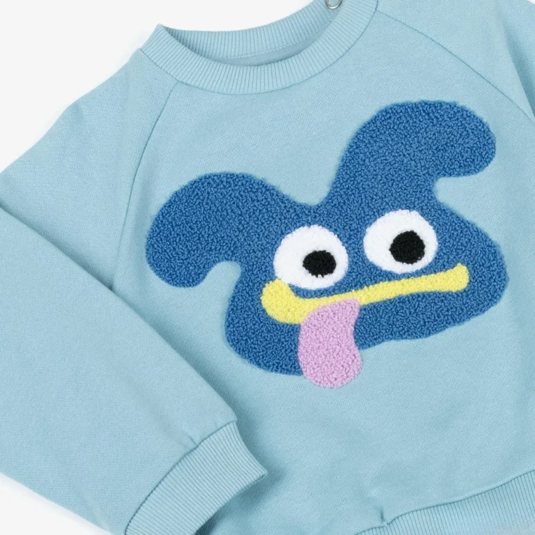 Blue chenille cartoon face with white eyes on a light blue kids sweatshirt