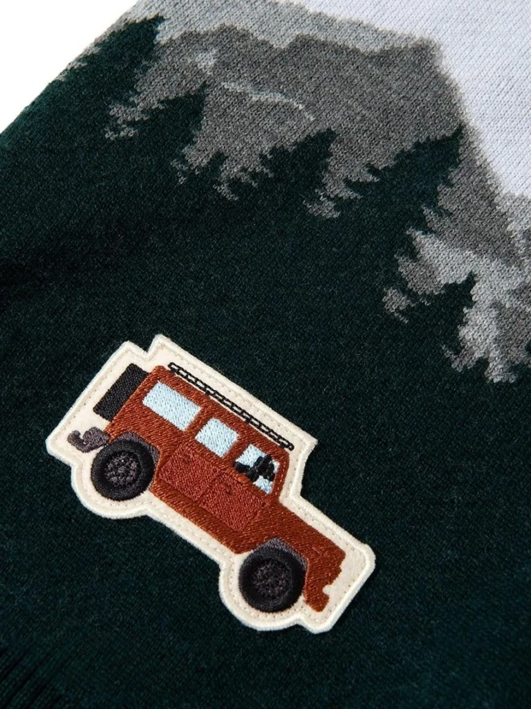 Embroidered off-road car patch on a dark green knit sweater