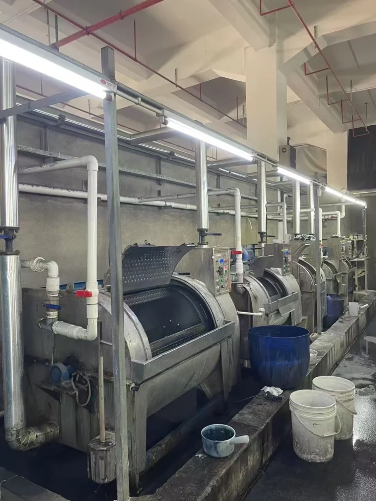 Row of industrial garment washing machines in a washing plant