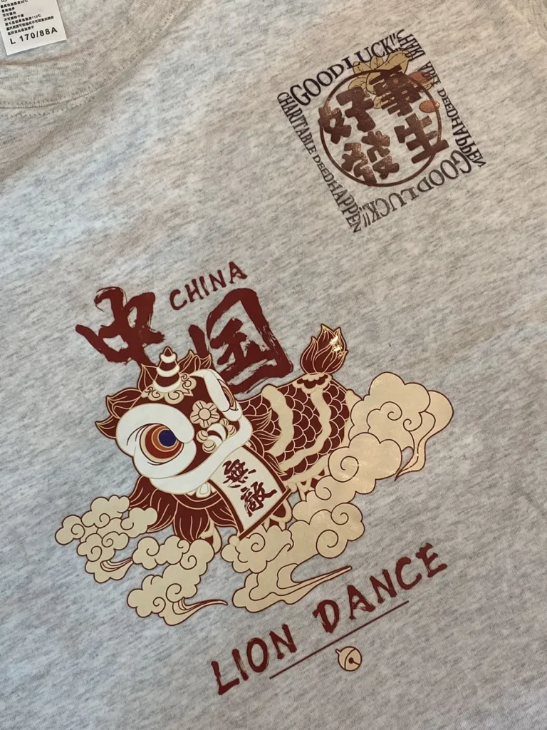 Red and beige lion dance print with Chinese characters on a grey T-shirt