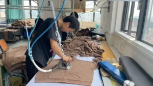 Worker cutting garment fabric at a cutting table