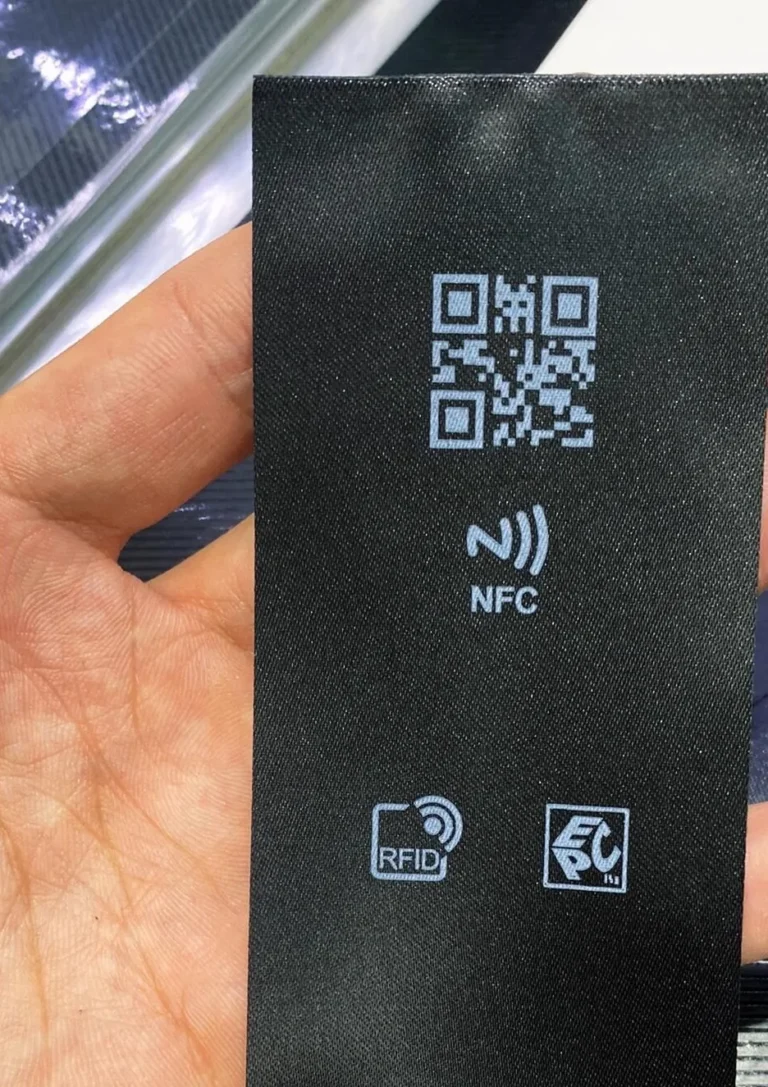 Black satin care label printed with a QR code and NFC and RFID icons